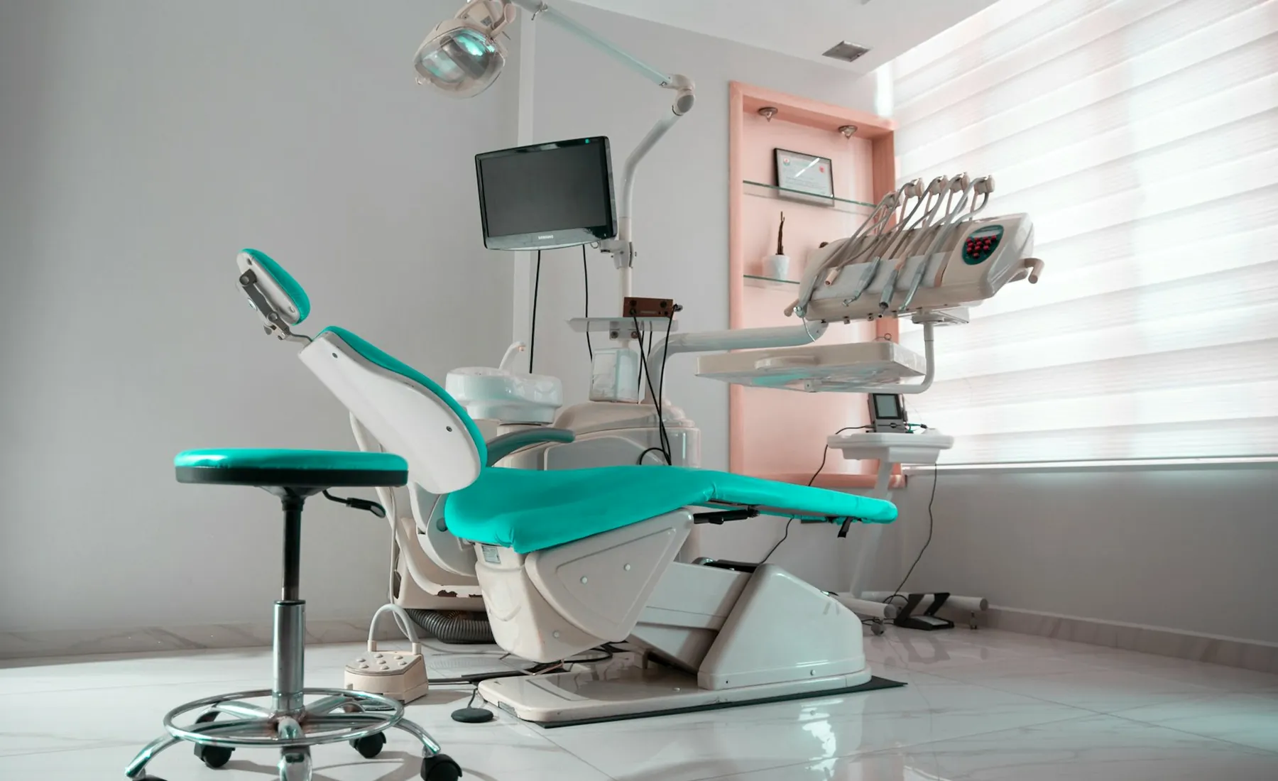 A bright dental treatment room with a teal chair